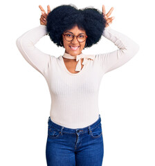 Young african american girl wearing casual clothes and glasses posing funny and crazy with fingers on head as bunny ears, smiling cheerful