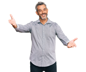 Middle age grey-haired man wearing casual clothes looking at the camera smiling with open arms for hug. cheerful expression embracing happiness.