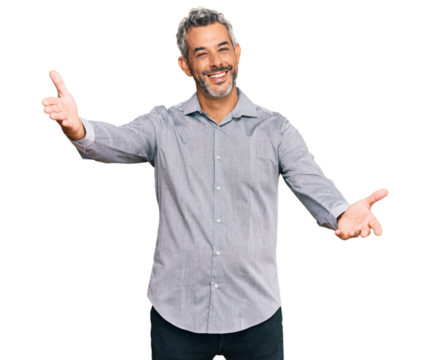 Middle age grey-haired man wearing casual clothes looking at the camera smiling with open arms for hug. cheerful expression embracing happiness.
