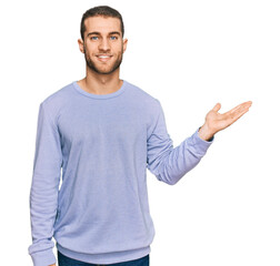 Fototapeta premium Young caucasian man wearing casual clothes smiling cheerful presenting and pointing with palm of hand looking at the camera.
