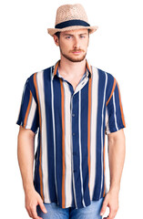 Young handsome caucasian man wearing summer hat skeptic and nervous, frowning upset because of problem. negative person.