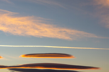 Lenticular clouds and cirrus clouds in the sky with the moon at dawn