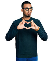 Young african american man doing heart symbol with hands in shock face, looking skeptical and...