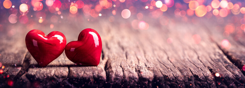 Two Red Marbled Glass Hearts On Rustic Wooden Table With Soft Pink Bokeh - Valentine's Day