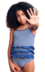 African american child with curly hair wearing swimwear doing stop sing with palm of the hand....