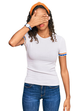Young african american girl wearing casual clothes covering eyes with hand, looking serious and sad. sightless, hiding and rejection concept