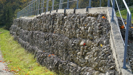 Fototapeta na wymiar Granite stones behind a metal grate for strengthening the slope. Stones behind the wire. grey texture. construction.