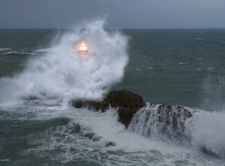 Fototapeta na wymiar Strong waves crash against the lighthouse.
