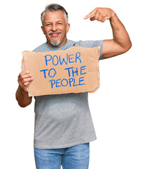 Middle age grey-haired man holding power to the people banner pointing finger to one self smiling happy and proud