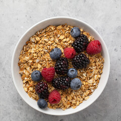 Granola with fresh raspberries, blueberries and blackberries for breakfast in a bowl. The concept of delicious and healthy food. Top view