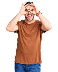Fototapeta premium Young hispanic man wearing casual clothes doing ok gesture like binoculars sticking tongue out, eyes looking through fingers. crazy expression.