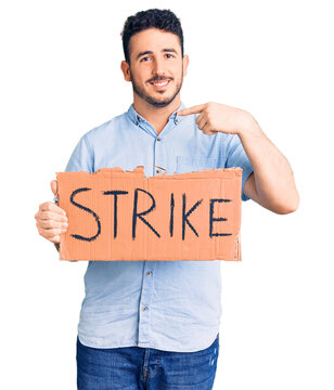 Young hispanic man holding strike banner cardboard pointing finger to one self smiling happy and proud