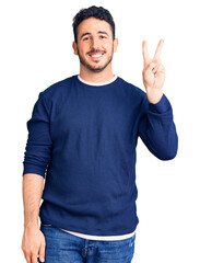 Young hispanic man wearing casual clothes showing and pointing up with fingers number two while smiling confident and happy.