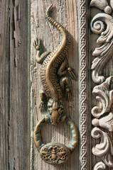 Old unusual iguana doorknob with knocker on an old wooden door
