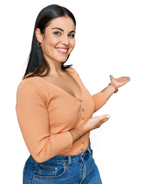 Young hispanic woman wearing casual clothes inviting to enter smiling natural with open hand