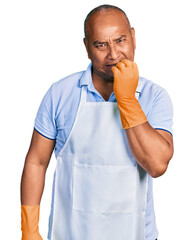 Hispanic middle age man wearing cleaner apron and gloves looking stressed and nervous with hands on...