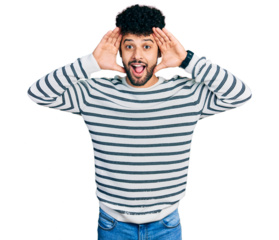 Young arab man with beard wearing casual striped sweater smiling cheerful playing peek a boo with hands showing face. surprised and exited