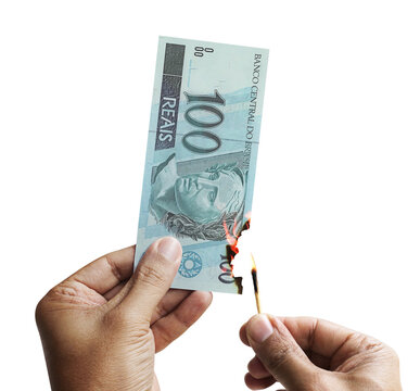 Burning money. Male hand setting a 100 reais bill on fire. Money from Brazil.  Transparent backgound 
