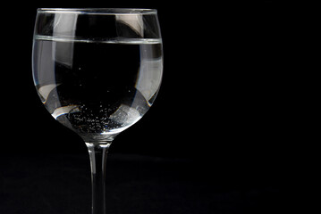 glass beaker with clear liquid isolated on black background