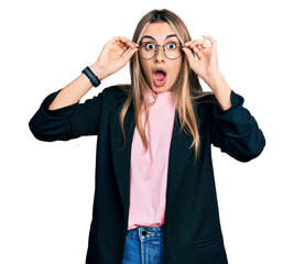 Hispanic young woman wearing elegant jacket and glasses afraid and shocked with surprise and amazed...