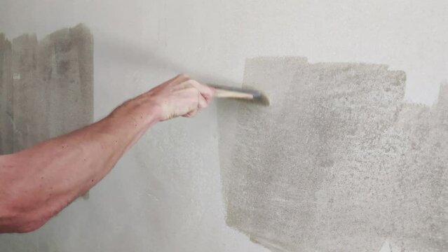 Man hand wall priming with brush.