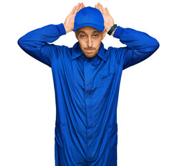 Bald man with beard wearing builder jumpsuit uniform doing bunny ears gesture with hands palms...