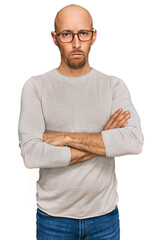 Bald man with beard wearing casual clothes and glasses skeptic and nervous, disapproving expression on face with crossed arms. negative person.