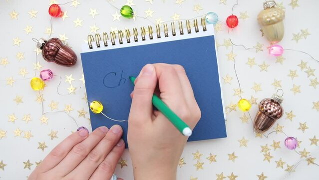 Female hand holds a pen, open blank notepad for writing. Christmas or New year wish or check list. 