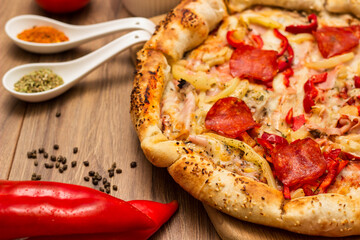 Tasty pizza with pepperoni, ham and peppers and pizza ingredients around the table