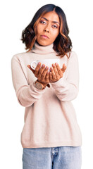 Young beautiful mixed race woman holding a cup of coffee thinking attitude and sober expression looking self confident