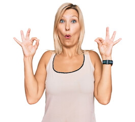 Middle age caucasian woman wearing casual clothes looking surprised and shocked doing ok approval symbol with fingers. crazy expression