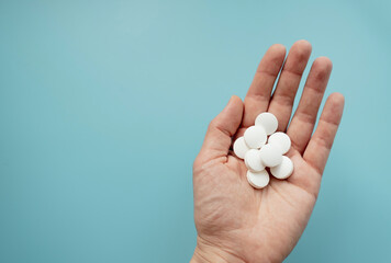 Close-up hand holding two tablets of pills. Top view. Healthcare and medication concept. copy space and place for text 