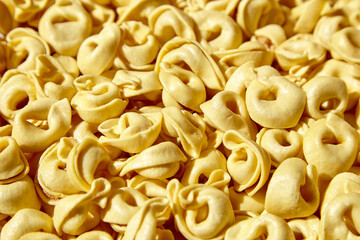 Tortellini pasta with prosciutto food background. Italian stuffed pasta