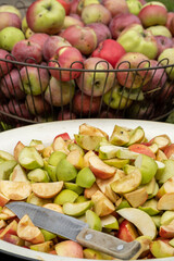 Cutting a lot of apples into pieces in the garden. Fresh red apple harvest. Cutting and preparing a fresh apple for eating. Cut fruits for jam cider or juice outdoors