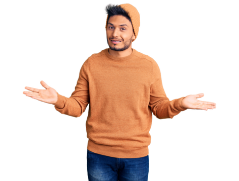 Handsome latin american young man wearing winter sweater and wool hat clueless and confused expression with arms and hands raised. doubt concept.