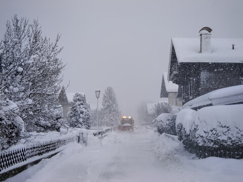 Mittersill, Austria - The street is covered with a high layer of snow and a plow is clearing the road. Snow disaster in the Alps.
