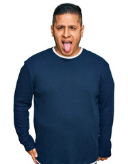 Young latin man wearing casual clothes sticking tongue out happy with funny expression. emotion concept.