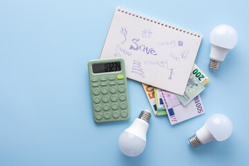 Save energy, accounting and saving money, energy saving light bulbs and notebook on a blue background, money spending planning, rising electricity costs, energy crisis in Europe