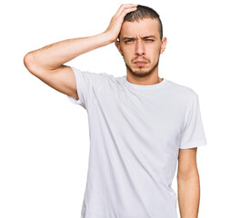 Hispanic young man wearing casual white t shirt confuse and wonder about question. uncertain with doubt, thinking with hand on head. pensive concept.