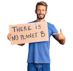 Handsome blond man with beard holding there is no planet b banner smiling happy pointing with hand and finger