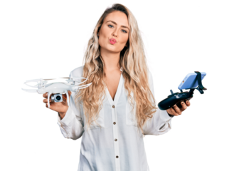 Young blonde woman holding television remote control looking at the camera blowing a kiss being lovely and sexy. love expression.