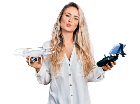 Young blonde woman holding television remote control looking at the camera blowing a kiss being lovely and sexy. love expression.