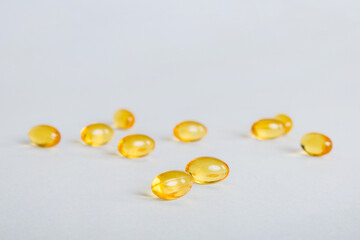 Heap of yellov pills on colored background. Tablets scattered on a table. Pile of red soft gelatin capsule. Vitamins and dietary supplements concept