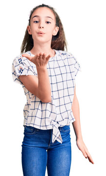 Cute hispanic child girl wearing casual clothes looking at the camera blowing a kiss with hand on air being lovely and sexy. love expression.