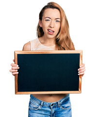 Young caucasian woman holding blackboard clueless and confused expression. doubt concept.