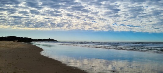 Panoramic view of Lighthouse Beach in Port Macquarie with the cloudy sky reflecting in the water