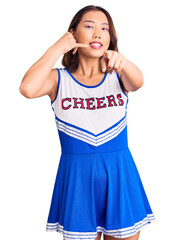 Young beautiful chinese girl wearing cheerleader uniform smiling doing talking on the telephone...