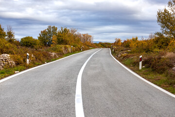 Empty two stripes car road. Roadway without cars. Autumn time in Krka national park, Croatia. Cloudy sky.