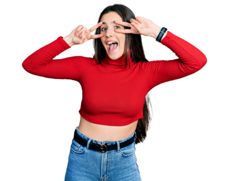 Young brunette teenager wearing red turtleneck sweater doing peace symbol with fingers over face, smiling cheerful showing victory