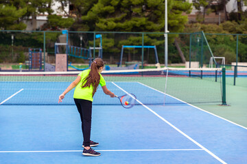 Young girl playing tennis. Serving the ball on tennis court.